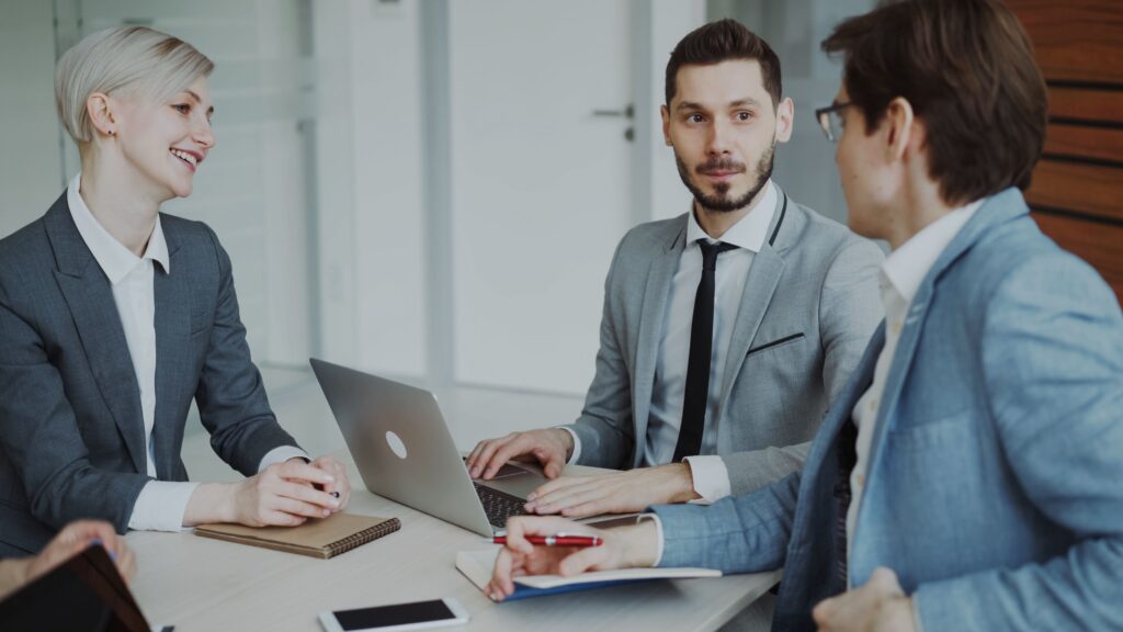 Business professionals discussing technology strategy around a laptop